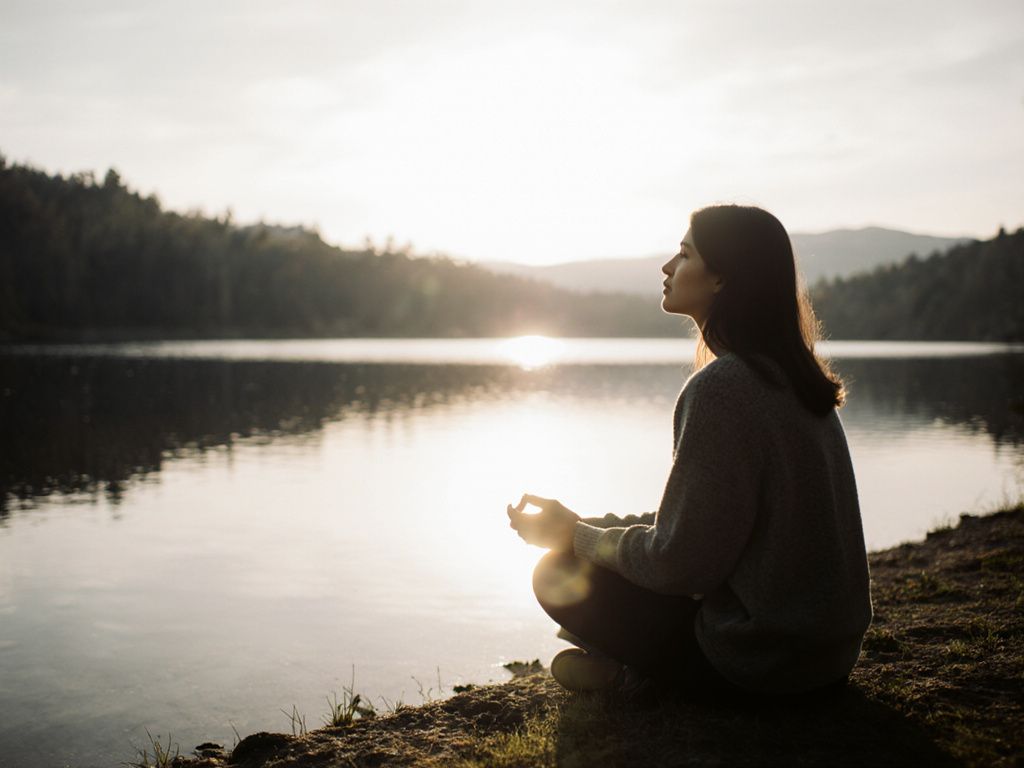 Person reflecting by calm lake representing self-awareness and mindful introspection